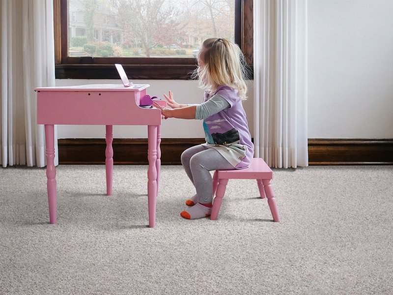 Girl playing toy piano in a room with soft carpet flooring